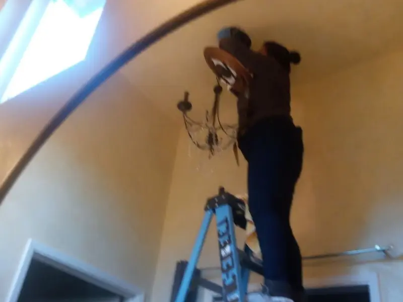 Electrician installing a chandelier in a Barnesville residence